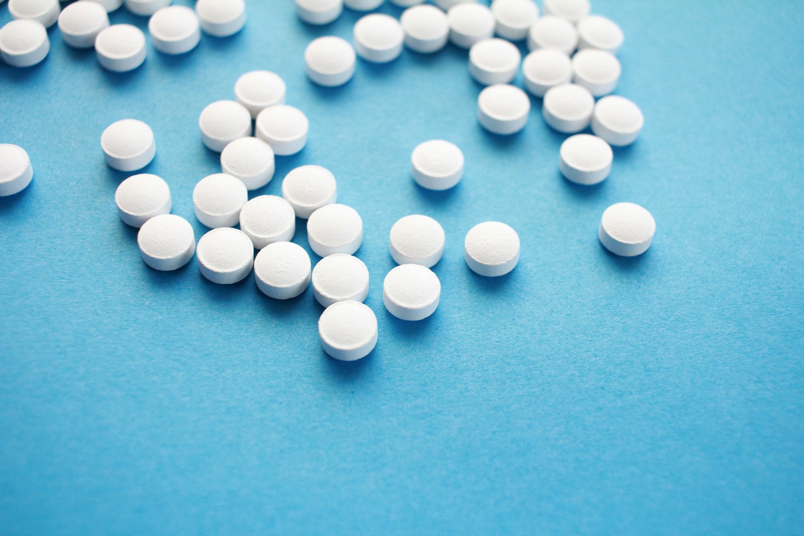 Comprimidos brancos sobre superfície azul, composição conceitual de medicamentos